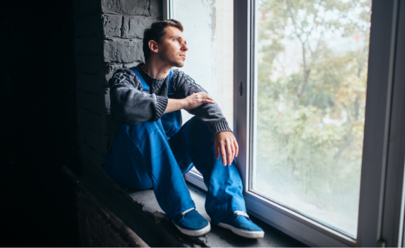 man sitting in window sill looking out the window in need of Outpatient Substance Abuse Treatment